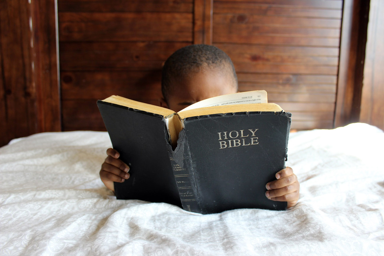 Journée de la mission - Enfant africain lisant une Bible en anglais